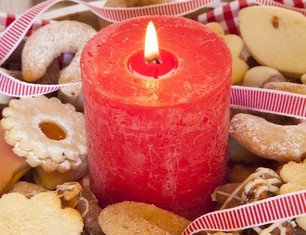 vertikale-aufnahme-einer-grossen-roten-brennenden-kerze-mit-weihnachtsplatzchen-und-verzierungen